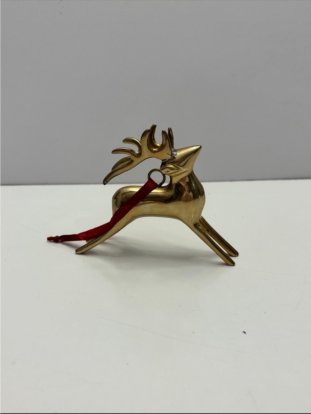 Vintage solid brass leaping reindeer Christmas ornament with a red ribbon